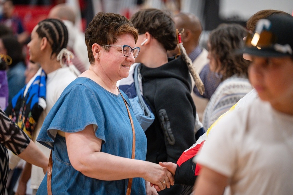 School Board Member Cathy Nathan shaking the hands of a AIE senior graduate.