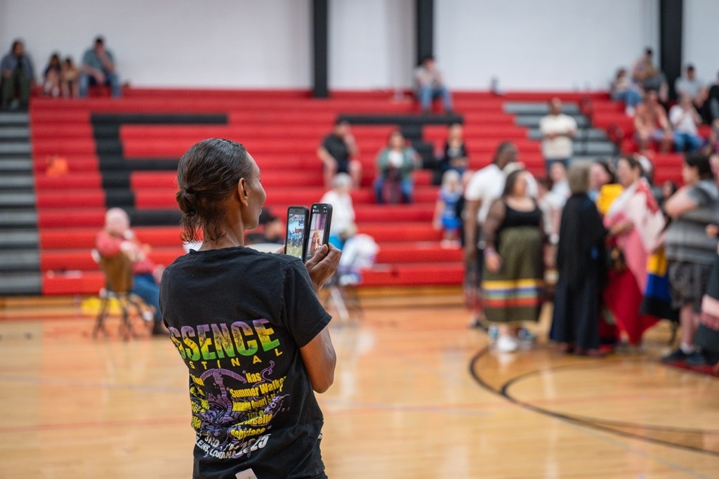 Proud family member recording and facetiming a family member during the eagle feather ceremony for seniors.