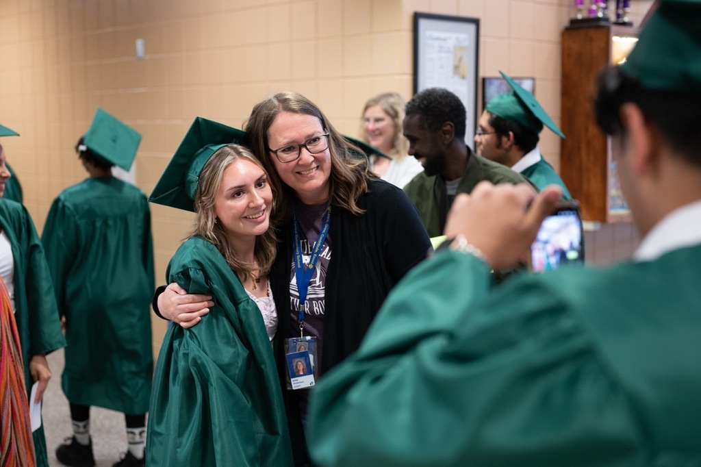 Mayo senior posing for a photo inside Riverside Elementary while another student takes a photo with their phone.