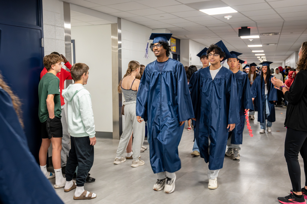 Seniors walking through Kellogg Middle School in cap and gown.