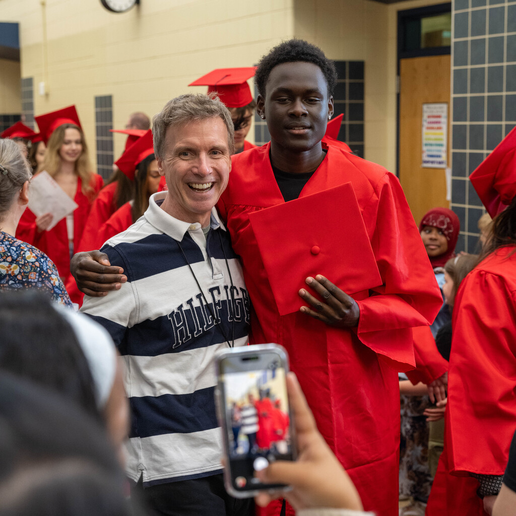 Senior posing for a photo in the hallway of Gibbs elementary with one of their Elementary teachers.