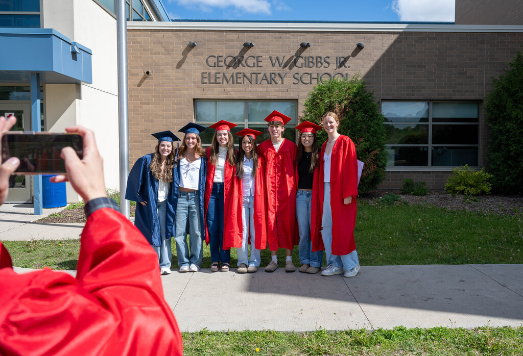 A group of Century and JM seniors locked in arms outside of Gibbs Elementary posing for a photo.