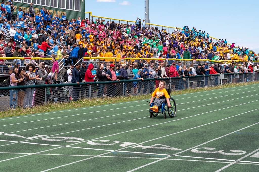 Student wheeling down the track in a wheelchair to the finish line.