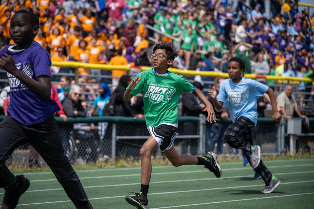 Three boys mid-stride as they run on the track.