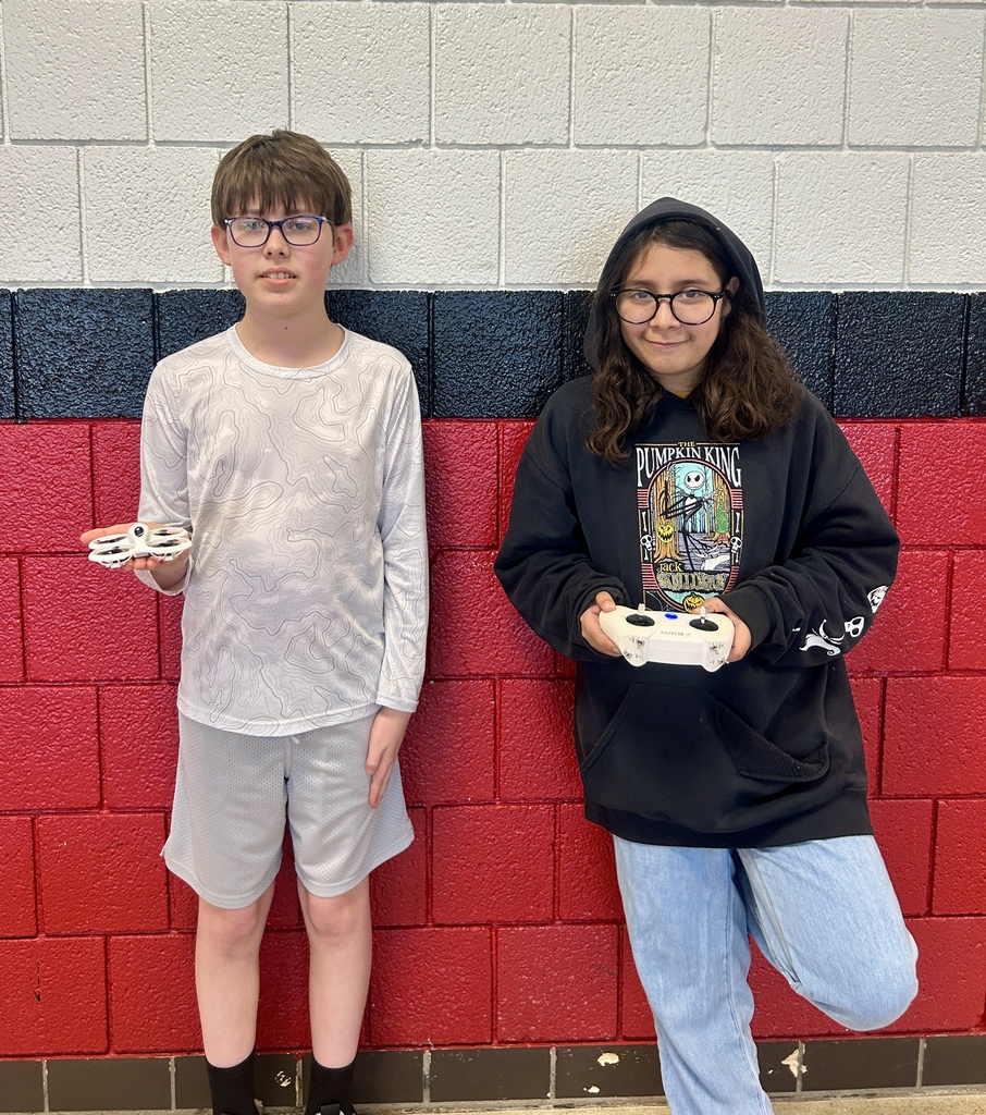 Two drone club members stood together posing  for a photo while holding a drone and controller