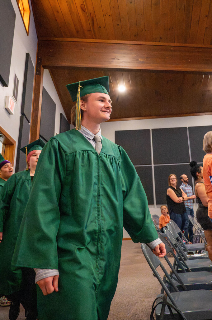 LEAP graduate walks into the hall where parents and families sit