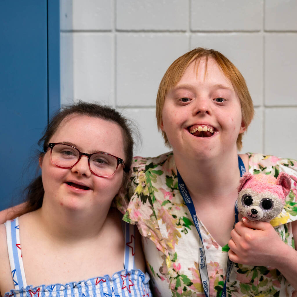 Two graduates in sundresses smile for the camera.
