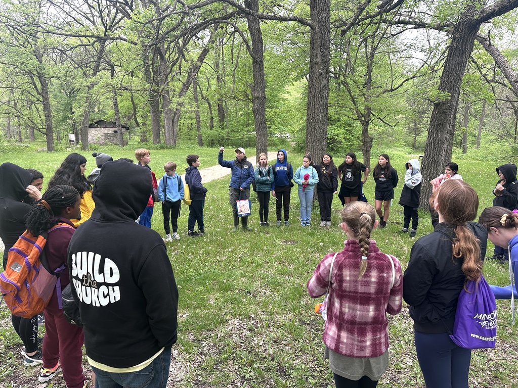 students in a circle, listening to adult