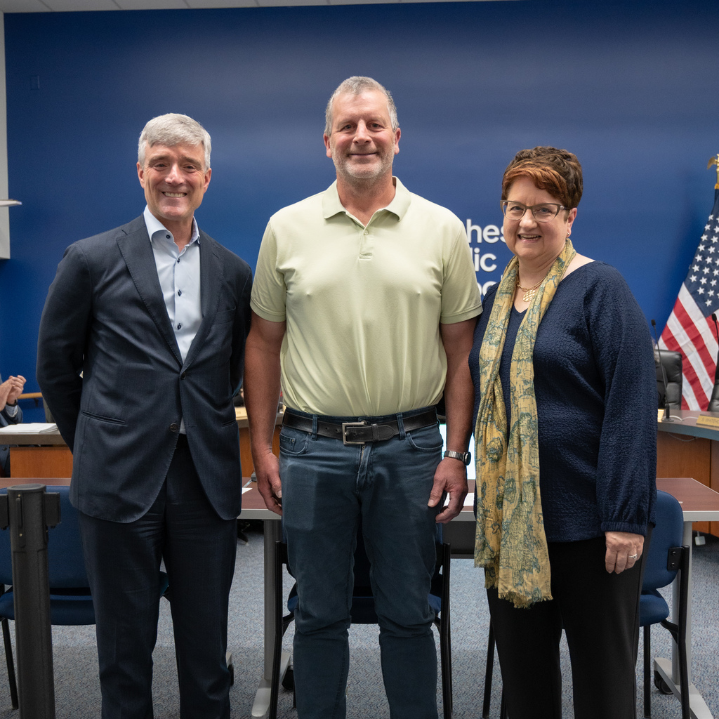 Retiree standing with Dr. Kent Pekel and Cathy Nathan.