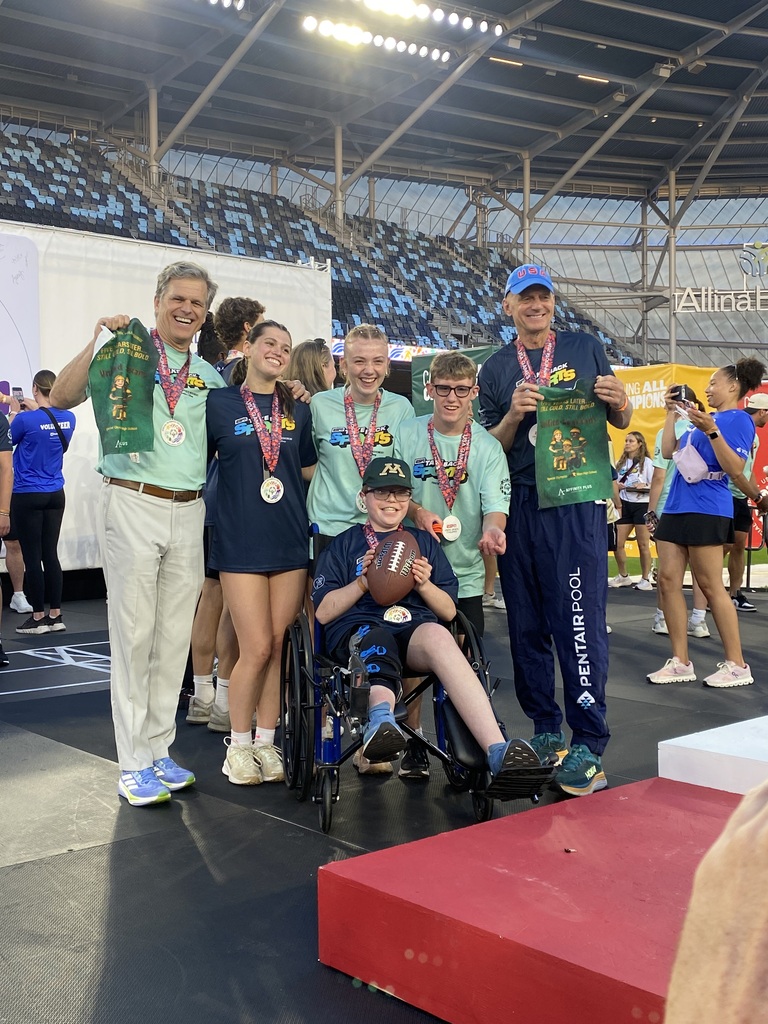 Group of students showing of their medals next to the podium.