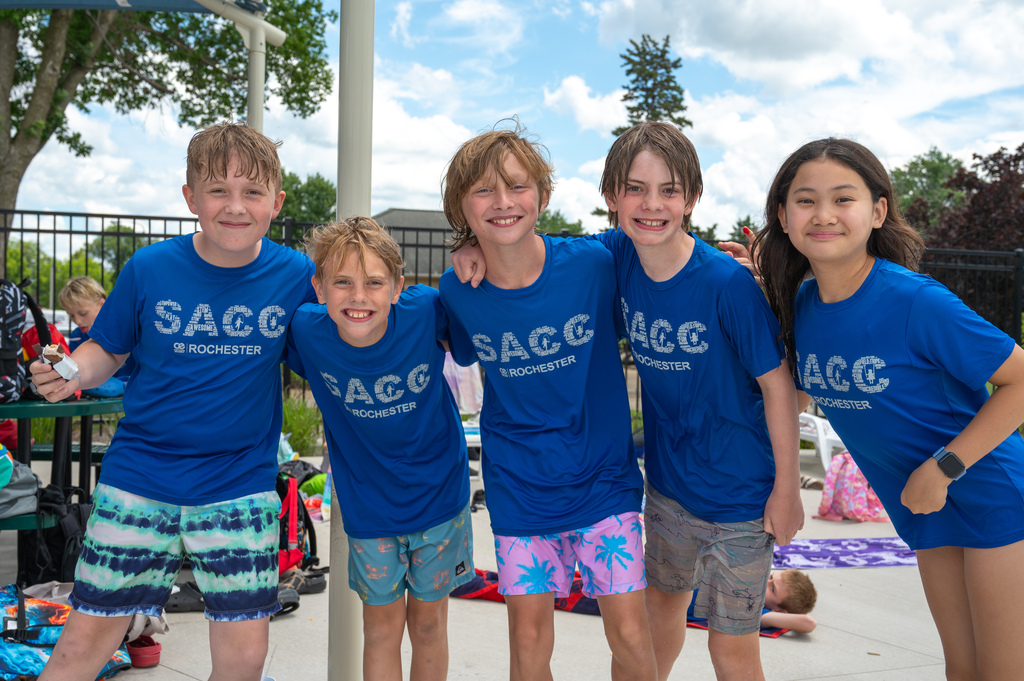 Five SACC students wearing their shirts and posing for a photo after swimming by the pool.