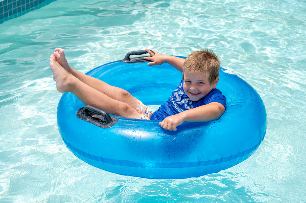 SACC student floating on tube with a smile on his face.