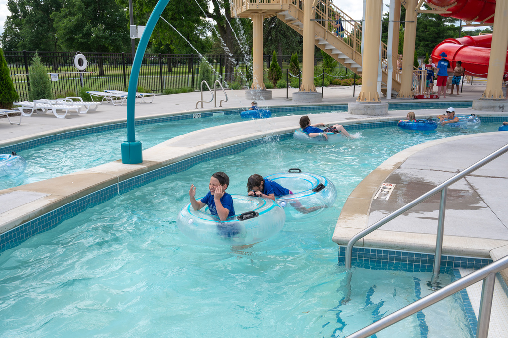SACC students smiling while tubing through the lazy river with one student holding onto another's tube.