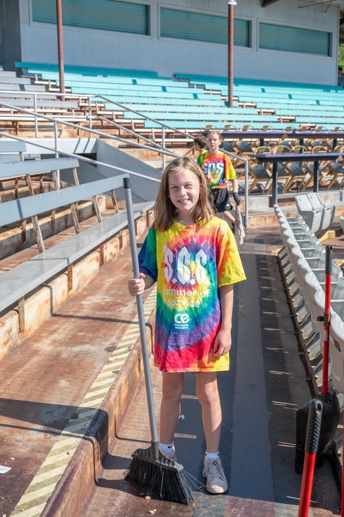 Student sweeping wearing an SOS shirt on the bleacher level of Honker Stadium.