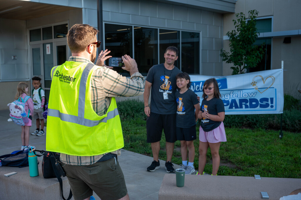 Longfellow staff member snaps a photo of a family in front of the school building