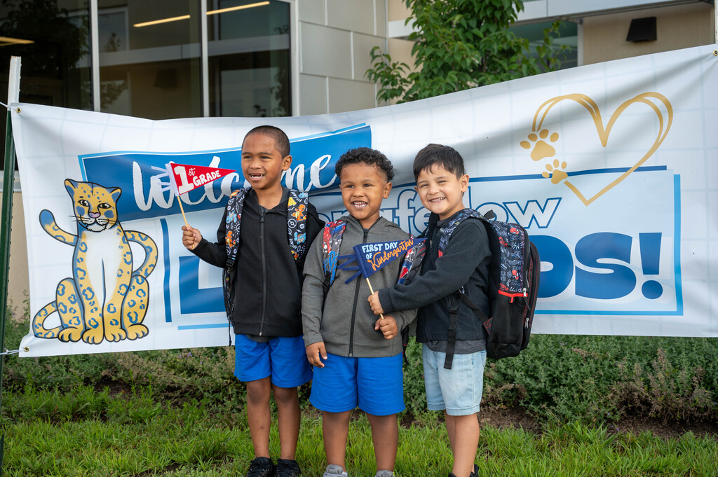 Longfellow students pose for a photo with flags commemorating their first day of first grade