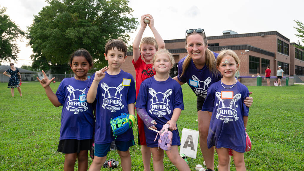 Tball team smiles and poses for the camera in matching shirts.