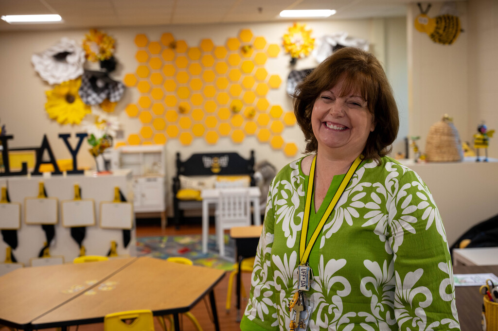 Teacher smiling and posing for a photo in her "beehive" themed classroom.