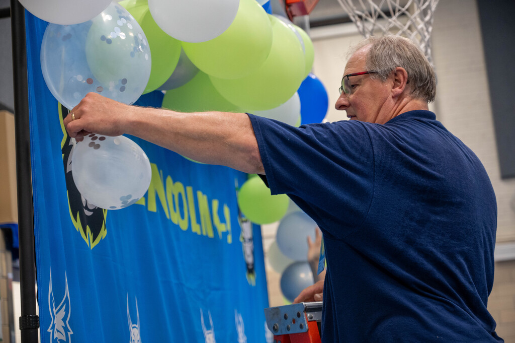 Janitor at Lincoln putting the final touches on a balloon display to welcome back students.