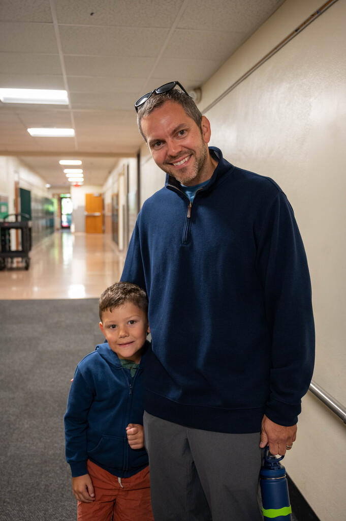 Parent smiling with student embracing his side as he half tucks a smile feeling shy.