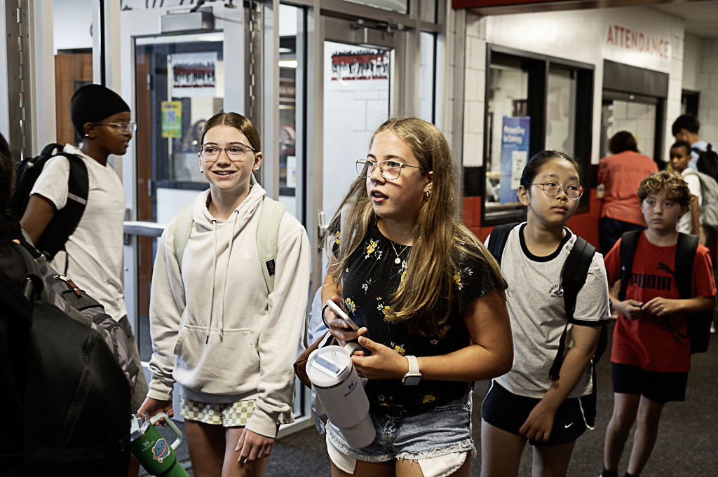 Group of students walking through the hallway looking for their lockers.