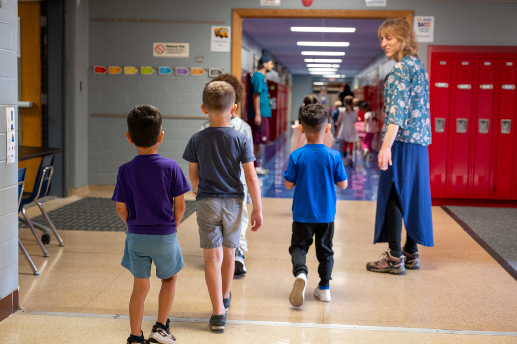 Students walking with a washington staff member to their classroom through the hallway.