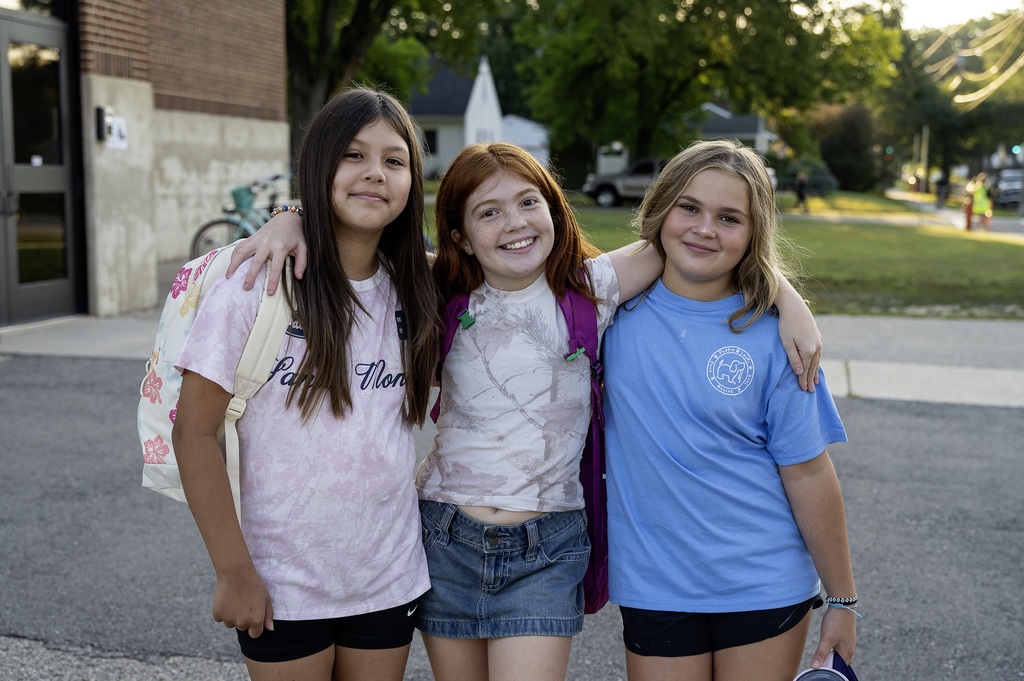 Three 5th grade students standing together with their arms around eachother for the first day of school.