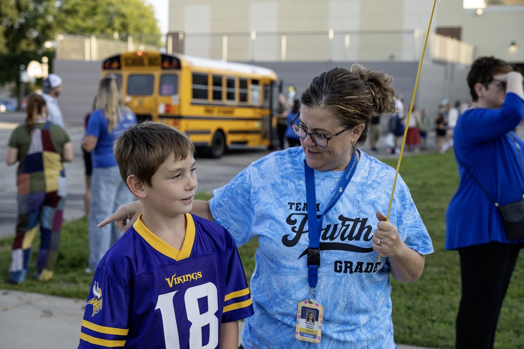 Teacher with yard stick talking to student about their Vikings' jersey.