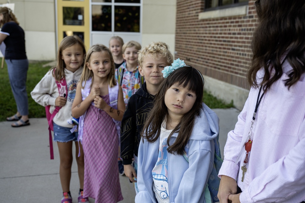 A line of 2nd grade students standing together as they wait for their classmates to arrive before the first bell.