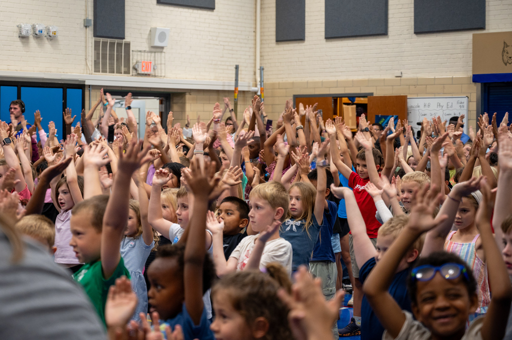 Students with hands in the air in the gym.