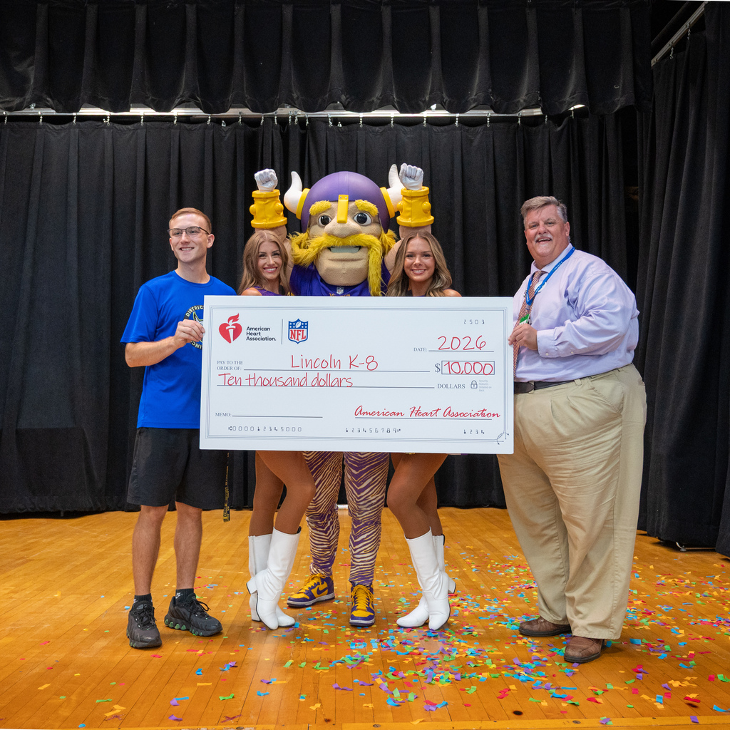 Vikings and Lincoln staff holding donation check. 