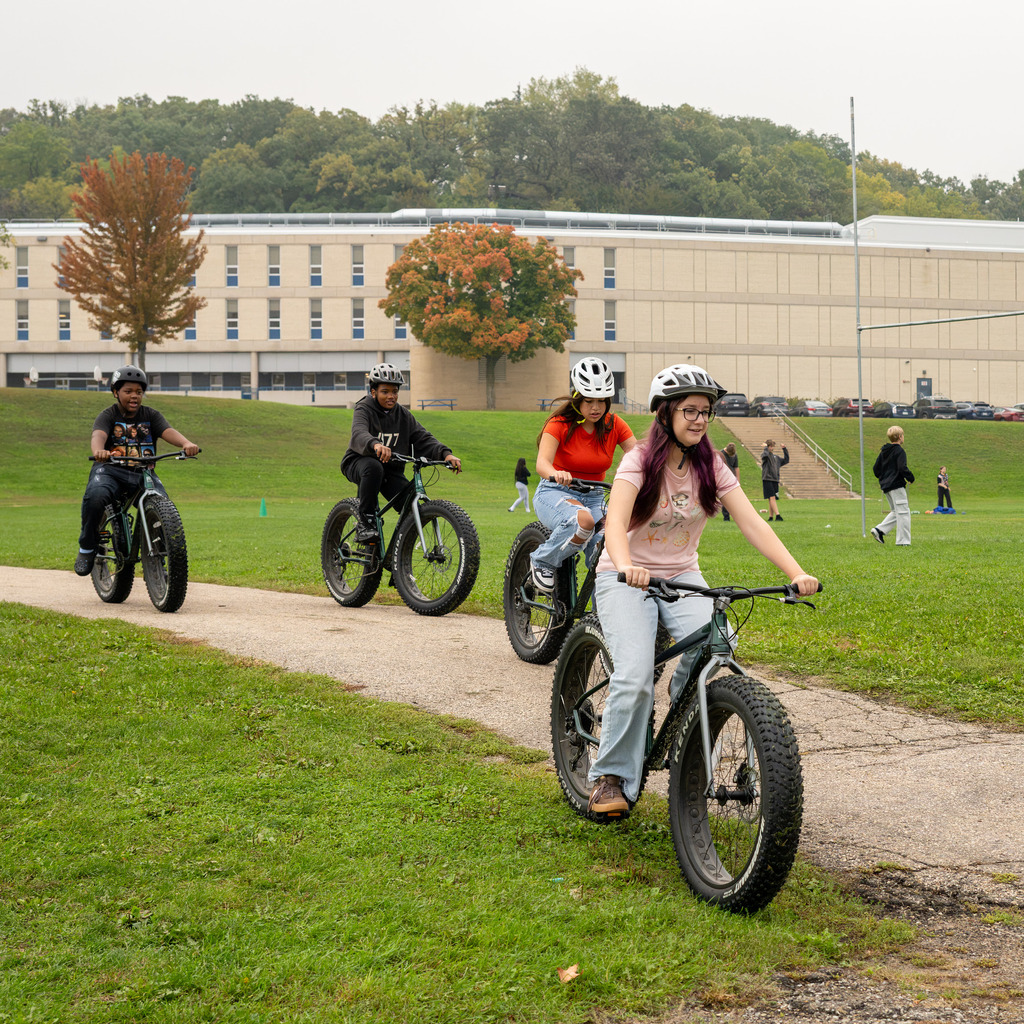 Middle schoolers in helmets start off on a bike ride.