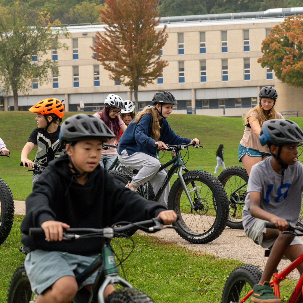 Middle schoolers in helmets start off on a bike ride.