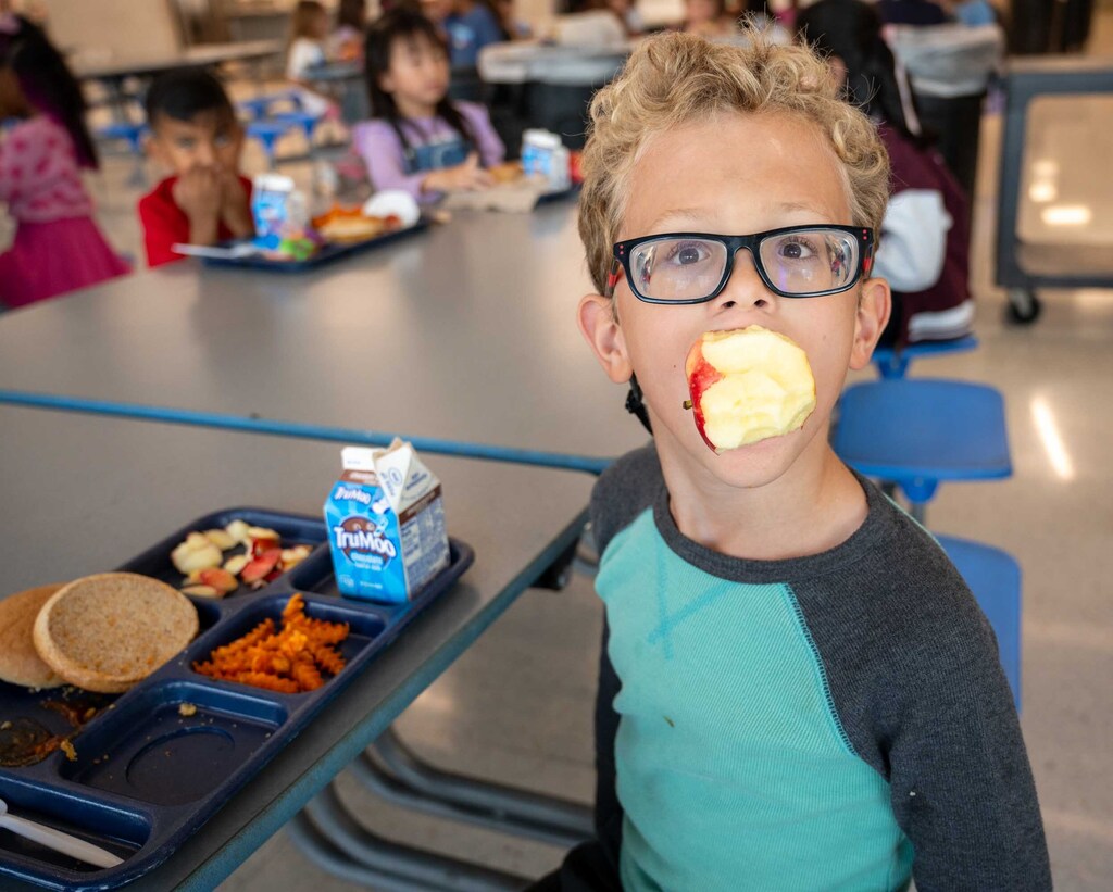 Student holding an apple in his mouth