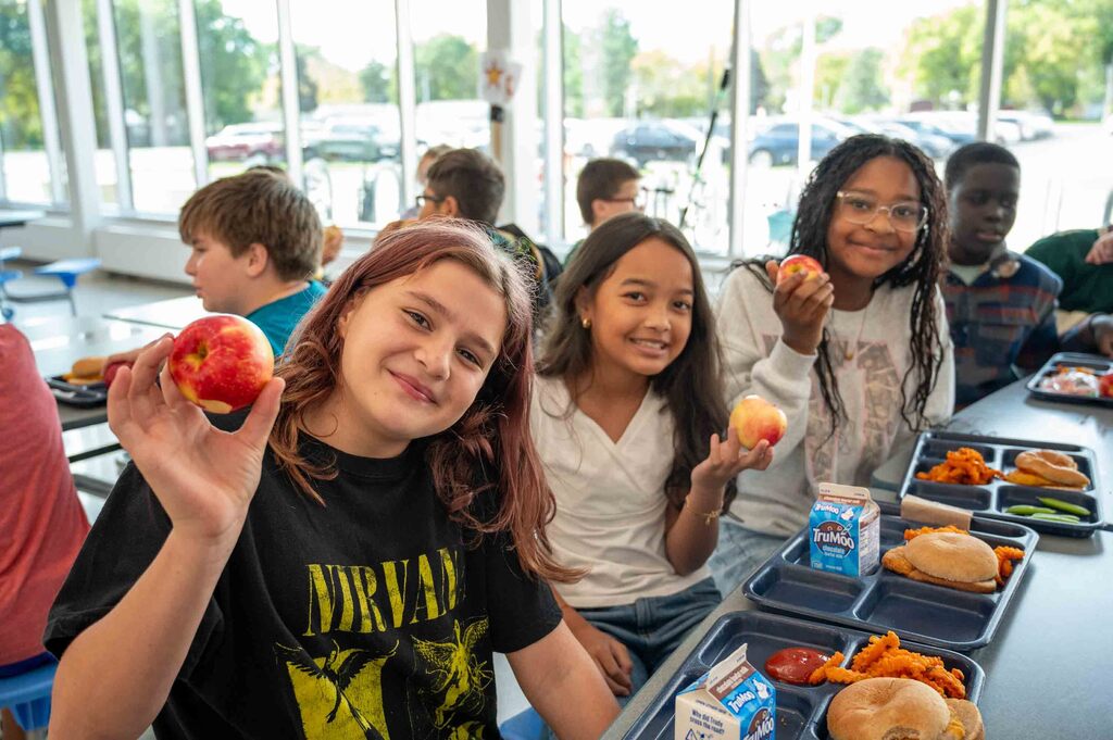 Students showing off their apples to the camera