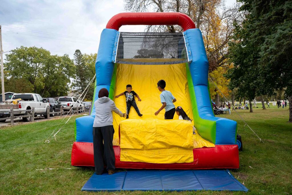 Kids slide down an inflatable slide in a park.