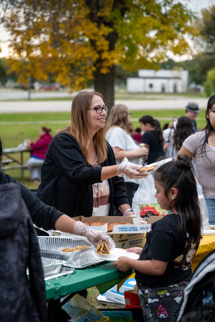 A woman hands out slices of pizza at a community event.