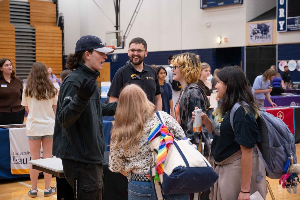 Students crowd around college table.