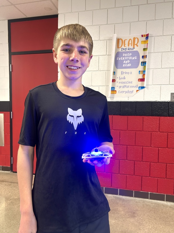 Student posing with one of the drones in hand