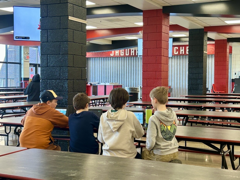 Students gathered around chromebook discussing drone club