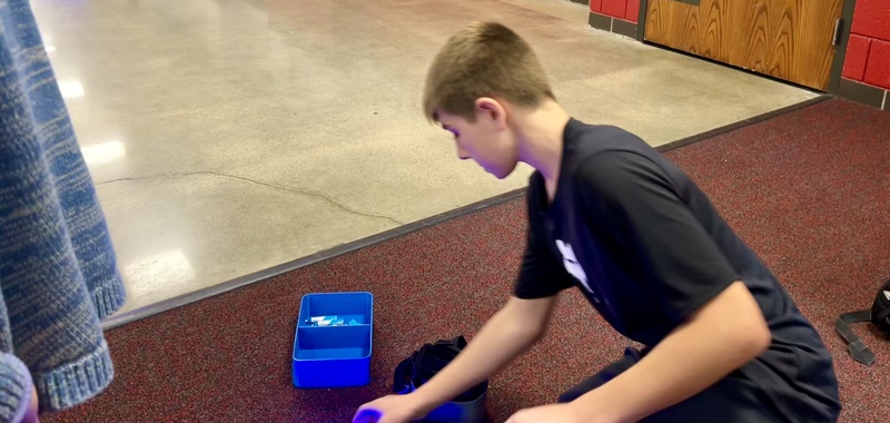 Student sat on the floor sorting through pieces and equipment for the drones