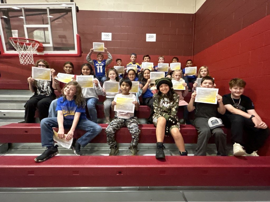 GMES October Students of the Month holding their certificates while sitting in the bleachers. 