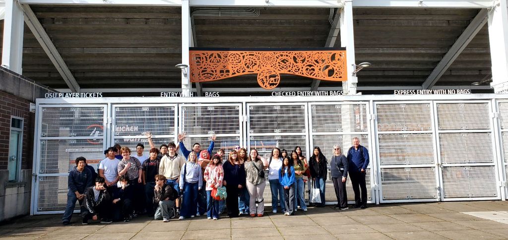 A group of people posing for a photo in front of a stadium with a metal gate.