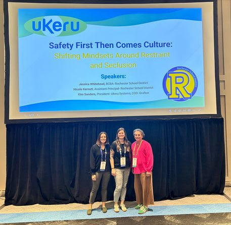 Three women stand in front of a conference presentation screen. The text reads "Safety First Then Comes Culture."