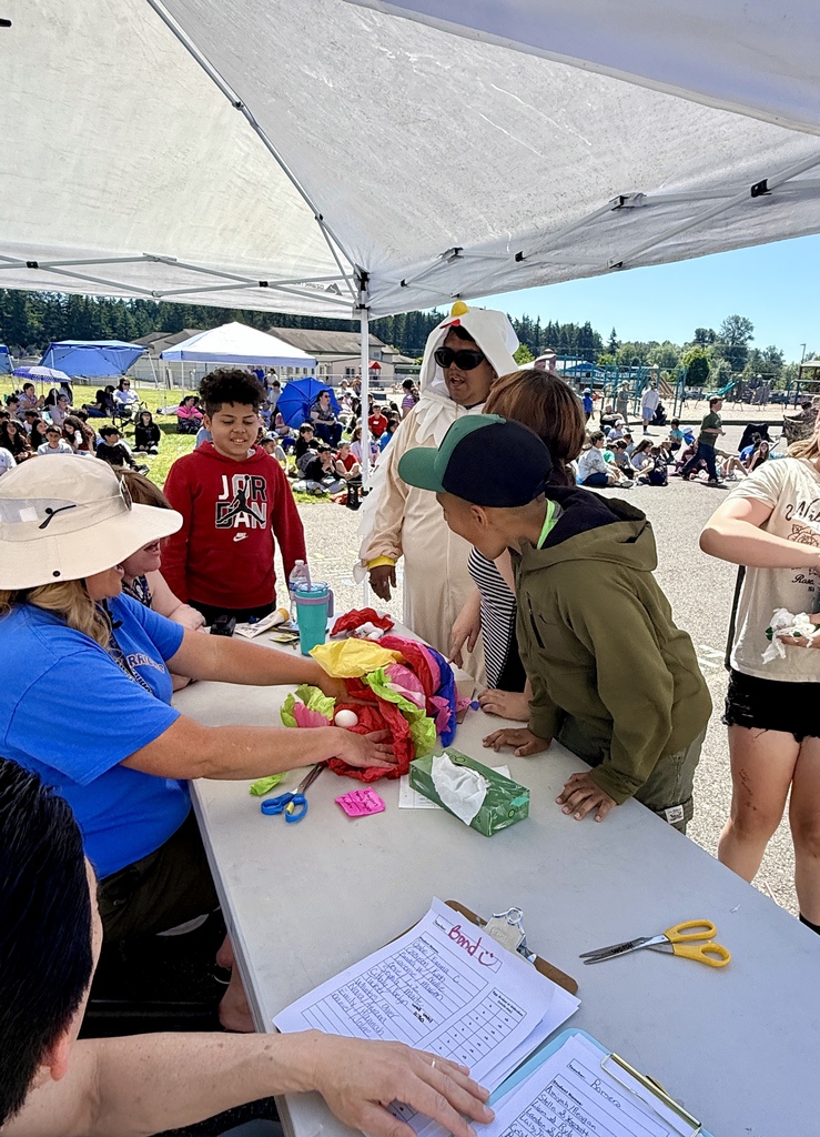A group of people under a tent, one person wearing a hat is holding an object.