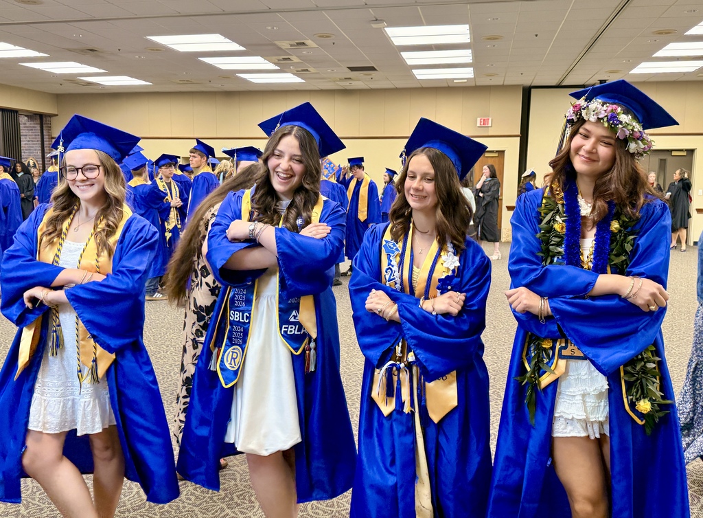 A group of women in blue gowns and caps stand next to each other in a room.