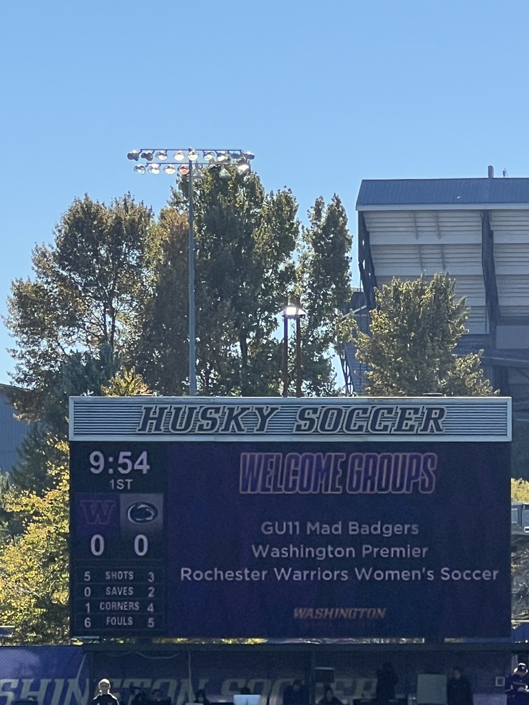 Scoreboard showing "Husky Soccer" and time "9:54" in front of trees and buildings.
