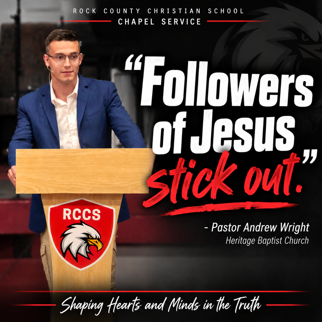 Man with glasses wearing a blue blazer standing behind a podium at Rock County Christian School  stating Followers of Jesus Stick Out