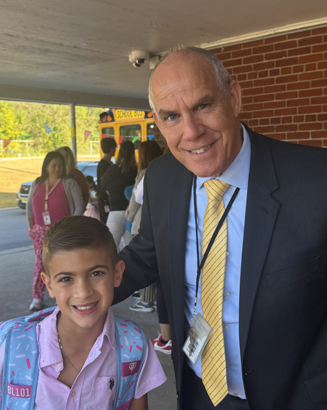 Superintendent posing with one male student at kdm front door