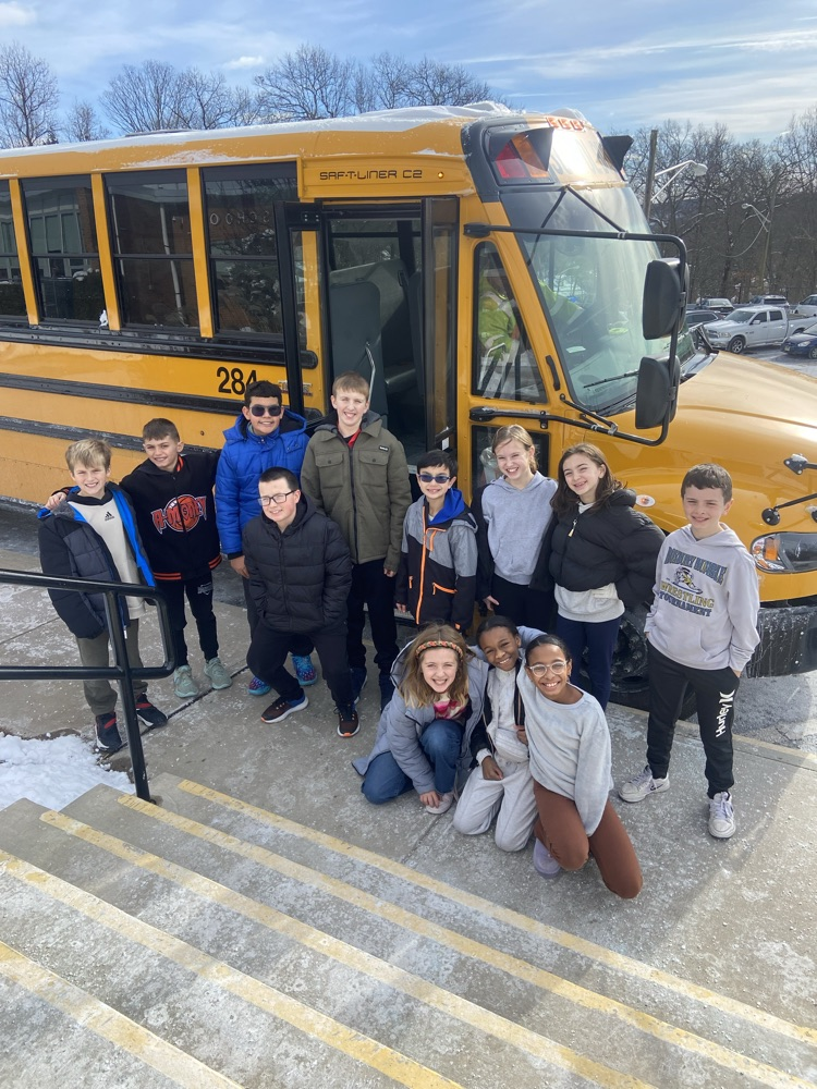 .Female and Male 4th grade students  posing in front of the school bus that took them to drop off their giving tree donations 